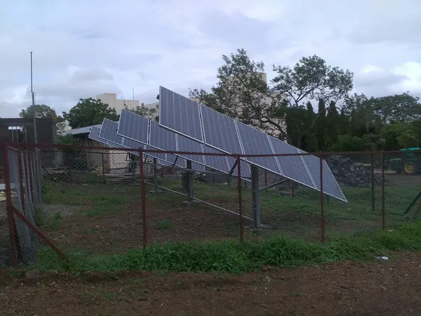 Rows of solar panels on a fenced farm site powering a borehole pump